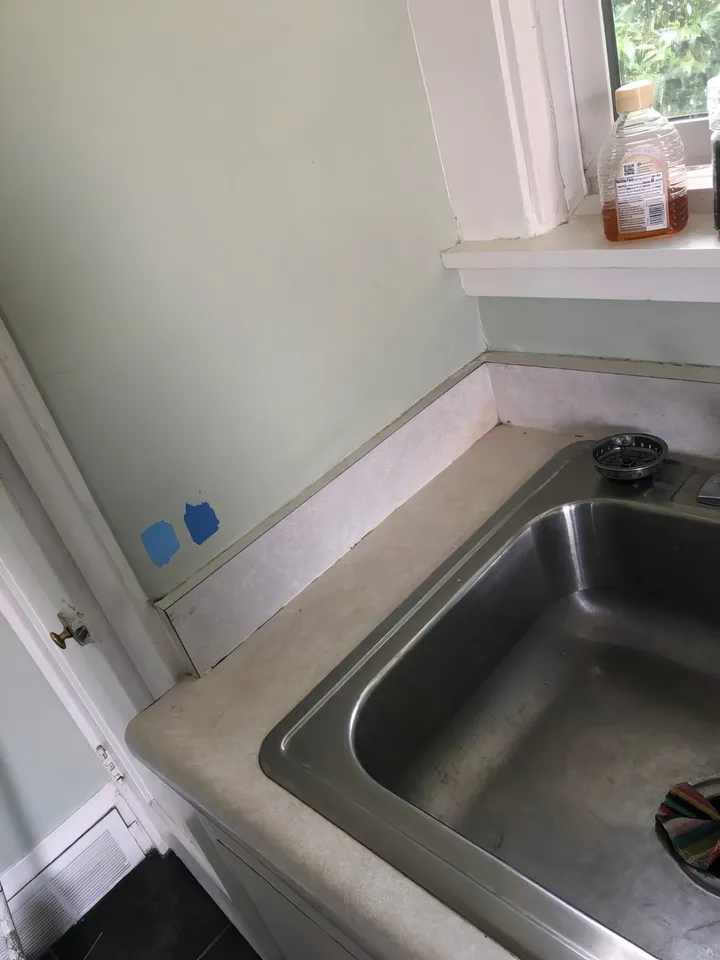 Kitchen before renovation showing old faucet, sink, and countertop